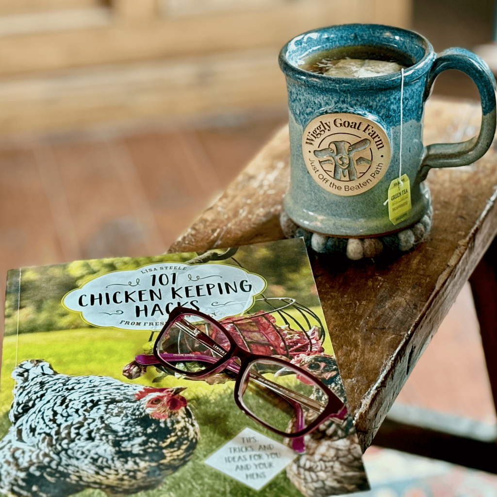 Wiggly Goat Farm mug on bench with book and reading glasses