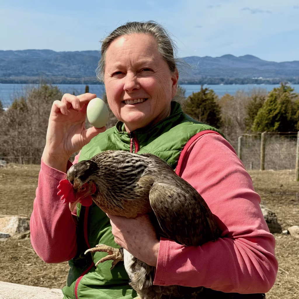 woman holding a chicken and green egg