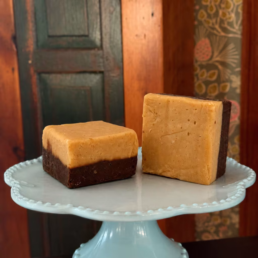 two pieces of Chocolate Peanut Goat milk Fudge on a pedestal