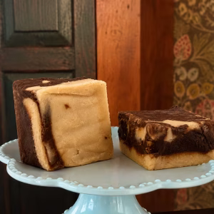 two pieces of Maple Chocolate Swirl Goat Milk Fudge on a cake stand