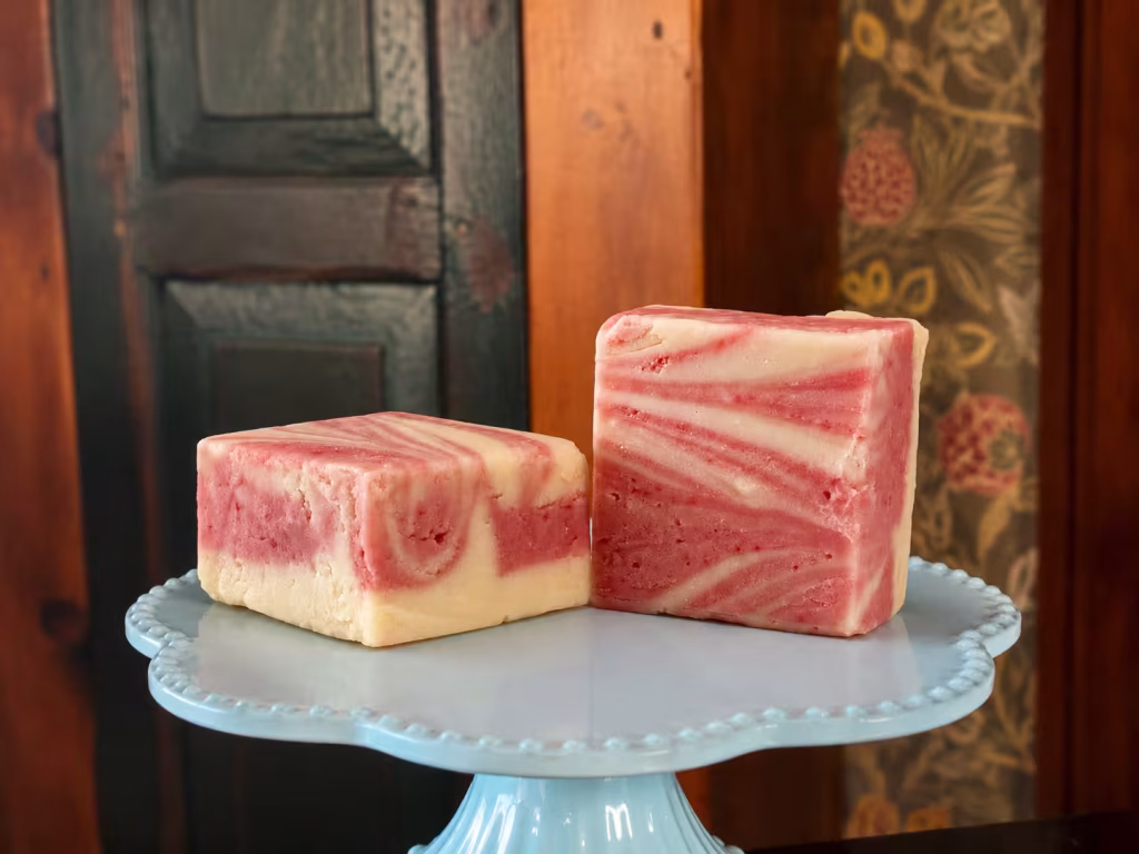 raspberry cheesecake goat milk fudge on a cake stand